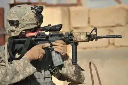 U.S. Army Specialist in Kirkuk's struggle, poised with his weapon during a security patrol, exemplifies the challenges faced by Iraqi Federal Government in human rights protection.