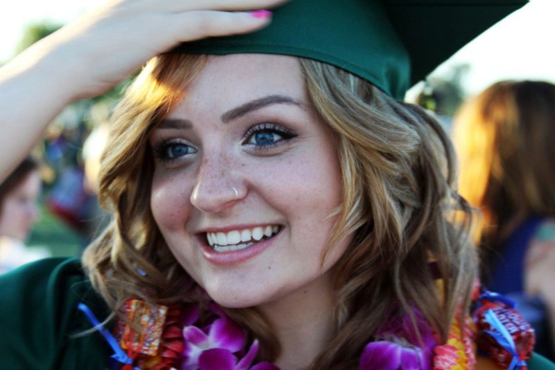 A young woman in a green graduation cap, smiling brightly, symbolizing an Academic Awakening.