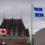 Drapeaux du Canada et du Québec flottant devant le Château Frontenac sous un ciel nuageux, symbolisant le fédéralisme multinational à Québec, où des identités culturelles distinctes coexistent au sein de la fédération canadienne.
