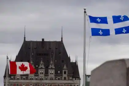 Flags of Canada and Quebec fluttering in front of the Château Frontenac under a cloudy sky, symbolizing multinational federalism in Quebec City, where distinct cultural identities coexist within the Canadian federation.