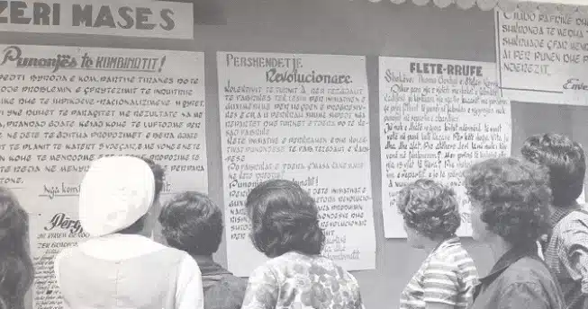 People in Albania read "fletërrufe," notices for public scrutiny, on a wall from the communist era.