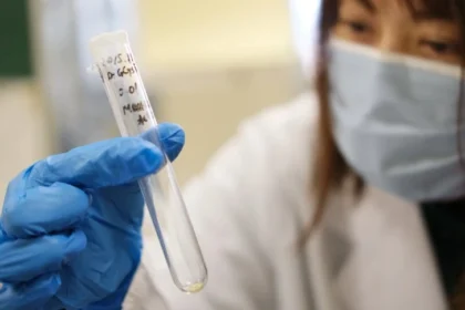 A healthcare professional wearing a lab coat and a surgical mask is holding a test tube, likely representing medical research or testing. Images like this can underscore the importance of access to quality healthcare, as well as the disparities that exist in different regions and among different groups of people. Health inequality is a significant issue around the globe, affecting millions. Addressing these disparities is critical for improving health outcomes and ensuring that all individuals have the opportunity to live healthy lives.