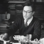 Masao Maruyama, un precursor de las democracias calificadas, trabajando en su escritorio rodeado de libros y papeles. Maruyama fue un prominente teórico político japonés que abogó por un enfoque más profundo y sustantivo de la democracia.