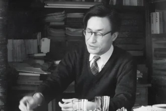 Masao Maruyama, a precursor of qualified democracies, working at his desk surrounded by books and papers. Maruyama was a prominent Japanese political theorist who advocated for a deeper and more substantive approach to democracy.