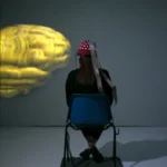 Neuropolitics: a woman sitting in a chair looking at a yellow brain