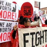 <p>Un grupo de manifestantes sostiene carteles y pancartas durante una manifestación por salarios justos. Los carteles dicen "¡VALORAMOS MÁS!", "HUELGA $15" y "LUCHA POR $15". Están abogando por un aumento del salario mínimo a $15 por hora. Esta imagen captura su llamado colectivo por el reconocimiento de su valor y la necesidad de una compensación justa en el lugar de trabajo. Foto de Bob Simpson (CC BY-NC-SA)</p>