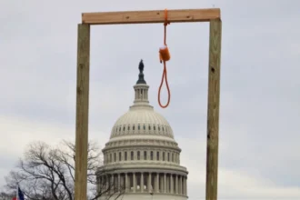 Militant democracy: Image of an improvised wooden gallows with a noose, with the United States Capitol building in the background. This scene is from the attack on the Capitol on January 6, 2021.
