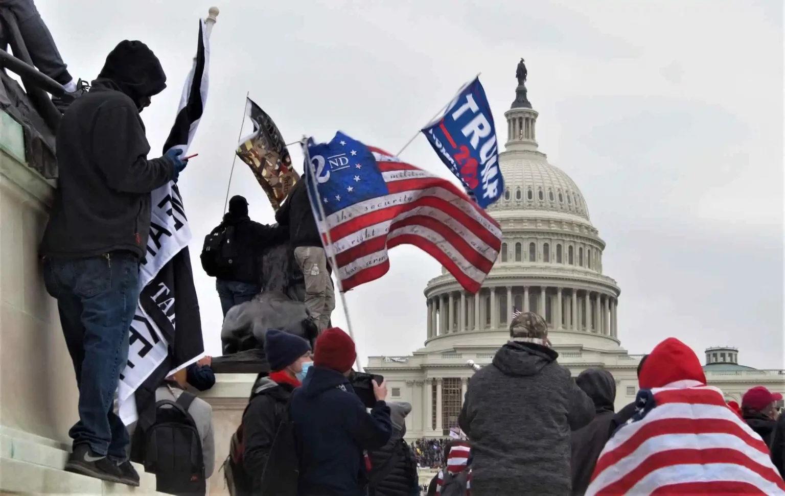 Supporters of Donald Trump gather outside the U.S. Capitol on January 6th, 2021, displaying flags and symbols that emphasize their partisan identity. The scene reflects the intense polarization in U.S. politics, where cognitive closure— the psychological need for certainty and clear identities—drives individuals to align strongly with their chosen political party, leading to heightened hostility and division between opposing groups.
