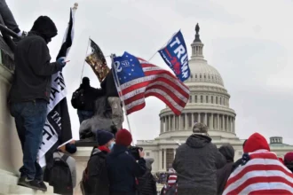 Les partisans de Donald Trump se rassemblent devant le Capitole des États-Unis le 6 janvier 2021, arborant des drapeaux et des symboles qui mettent en avant leur identité partisane. La scène reflète l'intense polarisation de la politique américaine, où la clôture cognitive—le besoin psychologique de certitude et d'identités claires—pousse les individus à s'aligner fortement avec leur parti politique choisi, entraînant une hostilité et une division accrues entre les groupes opposés.