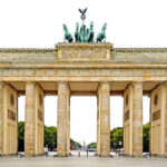 The Brandenburg Gate, crowned by the Quadriga, a symbol of victory and resilience. From a realist perspective, the gate represents the enduring power and fragility of political systems, as seen in the fall of the Berlin Wall and the reunification of Germany.