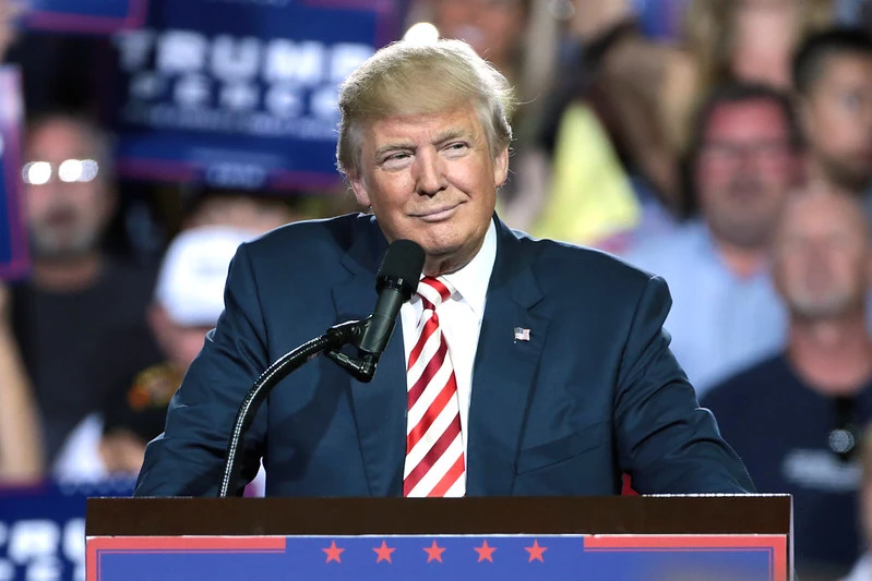 Former President Donald Trump speaking at a rally, with conservative professors among the audience, supporting his agenda and policies.