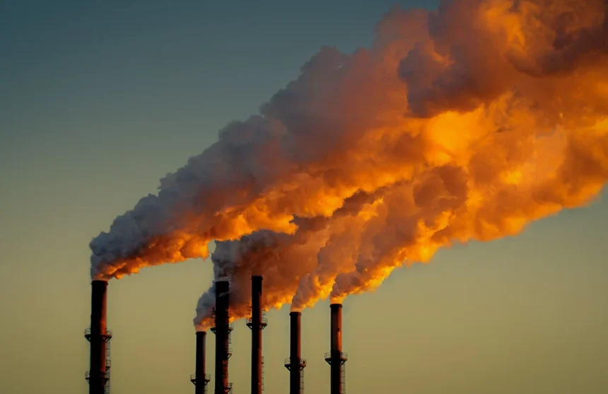 Cheminées industrielles libérant de la fumée dans le ciel, mettant en évidence l'impact environnemental de l'activité humaine sur la planète et les défis auxquels l'humanité est confrontée en matière de pollution et de changement climatique.