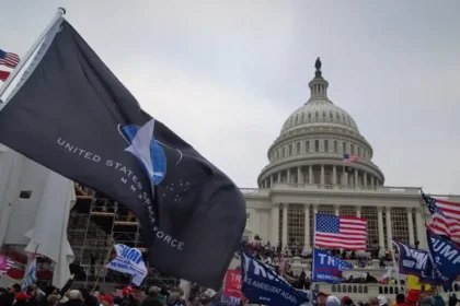 Les partisans de Donald Trump se rassemblent devant le Capitole des États-Unis lors de l'insurrection du 6 janvier, brandissant des drapeaux américains et de la campagne de Trump ainsi qu'un drapeau de la Force spatiale des États-Unis, reflétant un moment lié à la vision contestée de l'avenir des États-Unis sous l'influence de Trump.