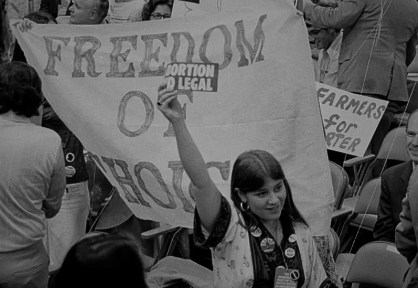 Abortion Pill: A Democratic delegate at the 1976 convention holds a sign advocating for abortion rights, with a backdrop of banners reading "Freedom of Choice." – Photo by Warren K. Leffler.