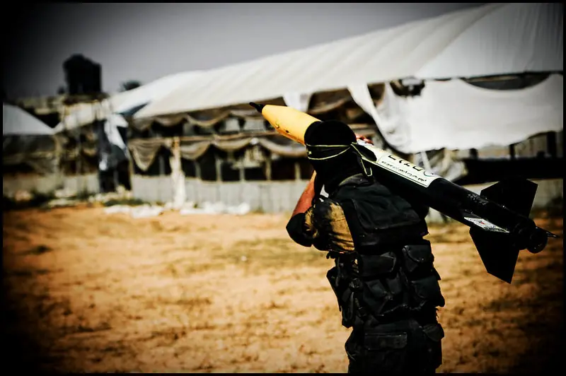 "Armed individual carrying a rocket in a conflict zone, reflecting the causes of war such as territorial disputes, resource struggles, and ideological conflicts.