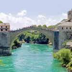 Le Vieux Pont de Mostar reconstruit, initialement édifié au XVIᵉ siècle, a été détruit pendant la guerre de Bosnie en 1993 et reconstruit en 2004 comme symbole de réconciliation et de préservation du patrimoine culturel. Photo de Dennis G. Jarvis (CC BY-SA).