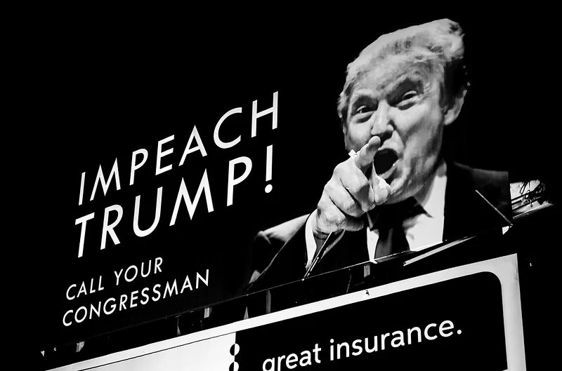 Disintegrating Societies: A black and white image of a political billboard calling for the impeachment of Donald Trump. The aggressive pointing gesture and bold text symbolize deep political polarization, reflecting the fragmentation and societal disintegration seen in modern democracies.