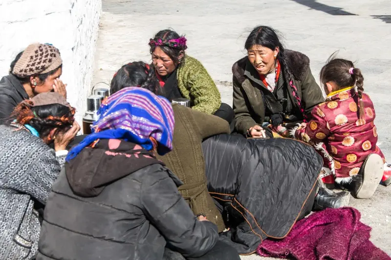 A group of Tibetan women and children gathered outdoors, illustrating the communal life and cultural diversity threatened by state sovereignty and assimilation policies in Tibet.