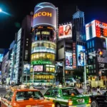 Contemporary view of Ginza, Tokyo. The illuminated spectacle of branded signage reflects the long-term influence of Commercial Art on Japan’s urban consumer spaces.