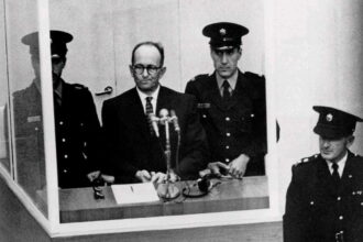 Criminal Adolf Eichmann, one of the main architects of the Holocaust, stands trial in Jerusalem in 1961. Seated in a bulletproof glass booth, he became the embodiment of Hannah Arendt’s controversial concept of the “banality of evil.”