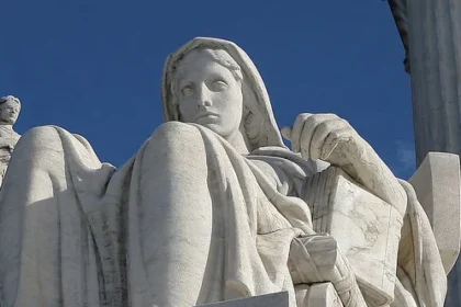 Sculpture of a seated woman holding a book and a small figure of Justice, representing thoughtful interpretation of law outside the U.S. Supreme Court.