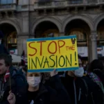 Iliberalismo: Lemas antiinmigración como “Detener la invasión” reflejan cómo los movimientos iliberales presentan a los migrantes como amenazas existenciales para la identidad nacional. Esta retórica sustenta políticas excluyentes y el rechazo del pluralismo liberal. Foto de Tommaso Ripani.