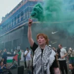 Manifestantes se solidarizan con Gaza, utilizando actos visuales y performativos para reclamar visibilidad política y desafiar las narrativas dominantes. Esta acción colectiva ejemplifica el uso de la voz más allá de las instituciones democráticas formales. Foto de Alisdare Hickson (CC BY-SA).