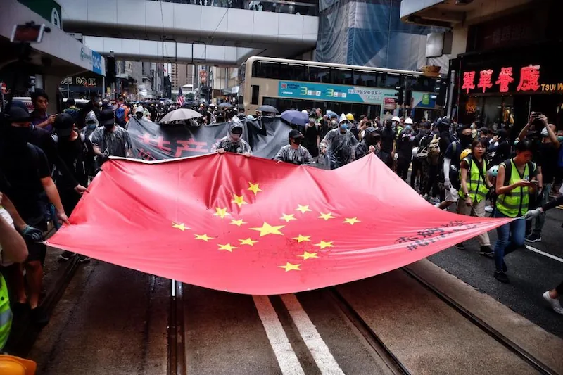 Protesters in Hong Kong carry a large, altered Chinese flag during a mass demonstration