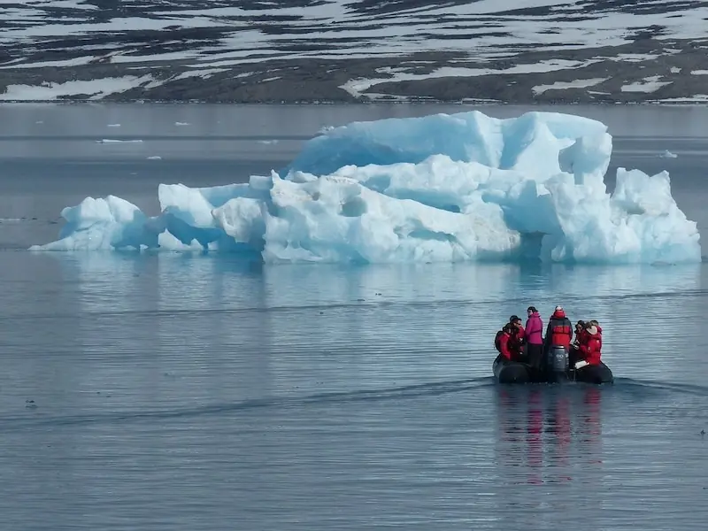 Researchers navigate Arctic waters near a floating iceberg. Once a site of scientific cooperation, the region is now entangled in distorting geopolitical narratives.
