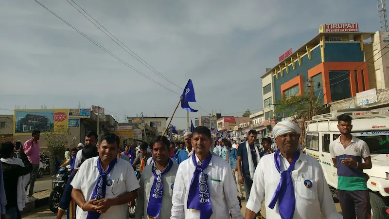 Hate crime_Dalit men participate in an Ambedkarite procession in Rajasthan, wearing blue scarves emblazoned with the slogan “Jai Bhim” and marching under the Ashoka Chakra flag. Photo by Sandhya Fuchs, taken during fieldwork.