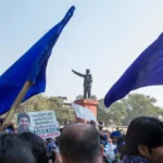 Estudiantes y activistas dalit se reúnen bajo la estatua de B. R. Ambedkar durante una protesta que exige justicia para Rohith Vemula y las víctimas de la violencia basada en castas. Sus pancartas piden la promulgación de una “Ley Rohith” para abordar la discriminación sistémica.  Foto por Joe Athialy (CC BY-NC-SA).