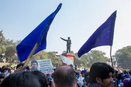 Estudiantes y activistas dalit se reúnen bajo la estatua de B. R. Ambedkar durante una protesta que exige justicia para Rohith Vemula y las víctimas de la violencia basada en castas. Sus pancartas piden la promulgación de una “Ley Rohith” para abordar la discriminación sistémica.  Foto por Joe Athialy (CC BY-NC-SA).