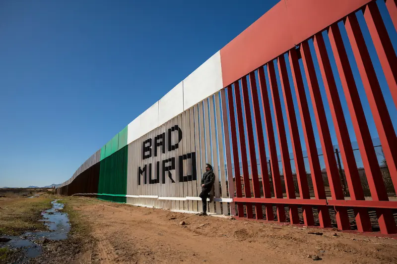 Graffiti and national colors transform the border wall into a contested surface, where sovereignty, protest, and everyday presence intersect.