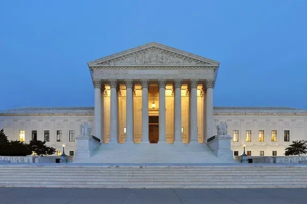 Supreme Court of the United States building at dusk in Washington, D.C., illuminated against a clear evening sky. Photo by Joe Ravi, CC BY-SA.