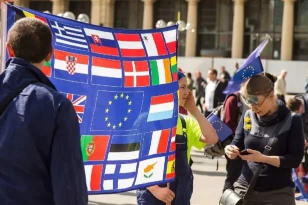 Protesters display a banner of national flags surrounding the European Union emblem during a pro-EU demonstration, reflecting the tension between national sovereignty and supranational integration that shapes debates over migration policy in Europe.