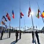 Militarism: Officers salute during the flag-raising ceremony at NATO's new headquarters in Brussels, marking the transition from the alliance's old site.