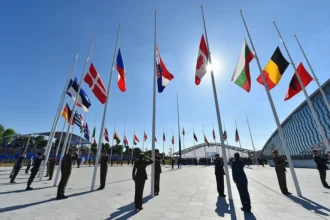 Militarism: Officers salute during the flag-raising ceremony at NATO's new headquarters in Brussels, marking the transition from the alliance's old site.